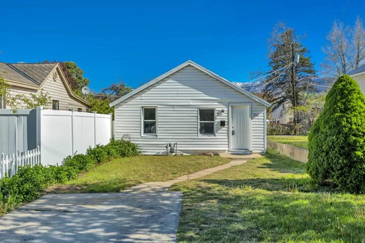 White siding exterior with a pitched roof, featuring a concrete driveway and walkway