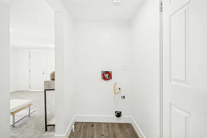 Dedicated utility area featuring wood-finish flooring and bright white walls