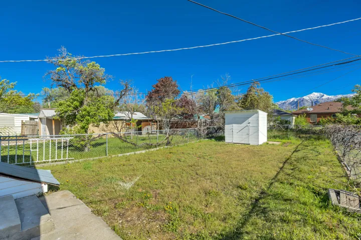 Expansive green space featuring a storage shed and chain-link fencing