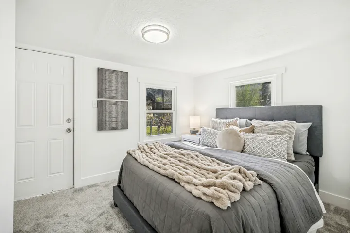 Bedroom featuring light-toned carpet flooring, white walls, and a multi-paneled door