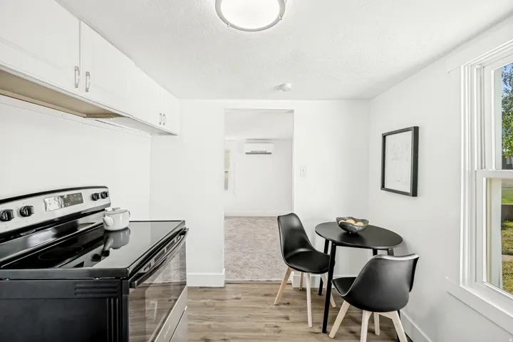Kitchen area featuring white cabinetry, a black electric range, and wood-finish flooring