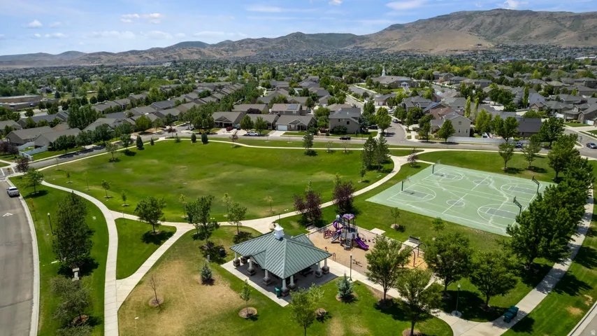 Expansive green space featuring a large central lawn, a multi-sport court, a covered gazebo, and a children's play area