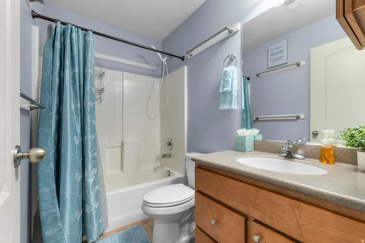 Bathroom with a wood-finish vanity, integrated sink, and gray countertop