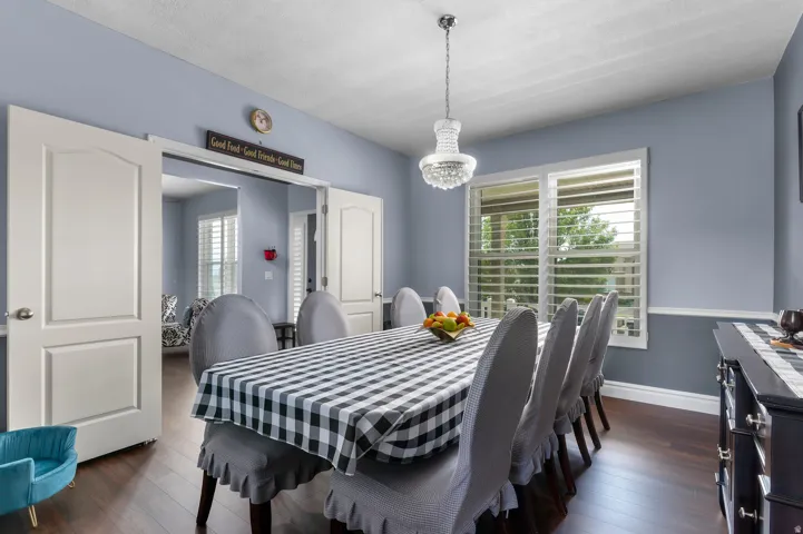 Dining area with wood-finish flooring, light blue walls, and a crystal chandelier