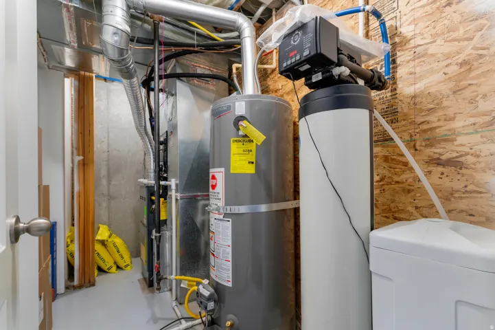 Utility room featuring a water heater, furnace, and water softener system