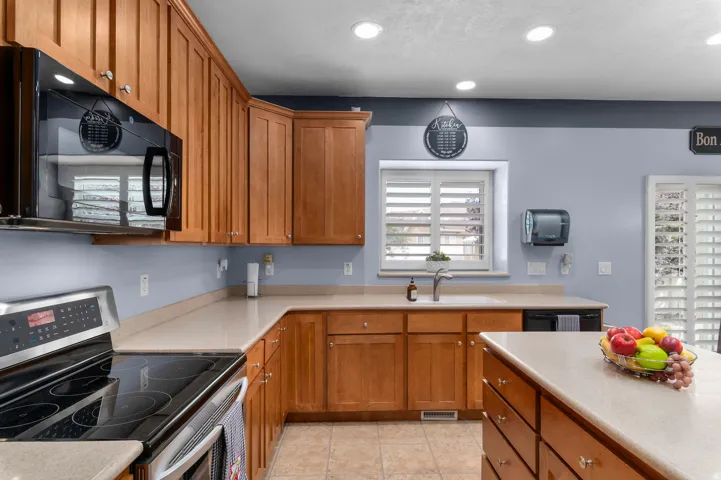Kitchen featuring warm wood cabinetry, light countertops, and recessed lighting