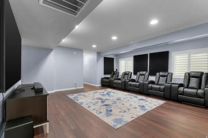 Entertainment room featuring recessed lighting, dark wood-finish flooring, light blue walls, and white plantation shutters