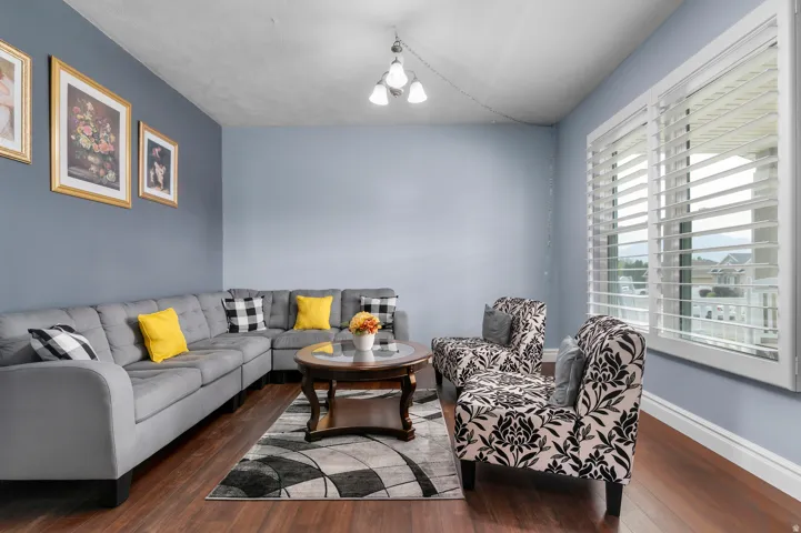 Living area featuring wood-finish flooring, light blue wall paint, and white baseboards