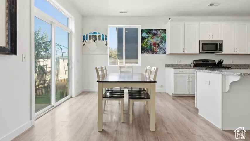 Bright eat-in kitchen with granite countertops, white cabinetry, stainless steel appliances, and a sliding glass door to the backyard.