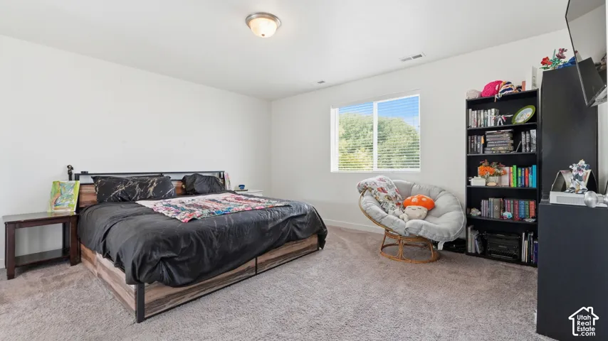 Large bedroom with plush carpet and a window overlooking mature trees and beautiful mountain view.