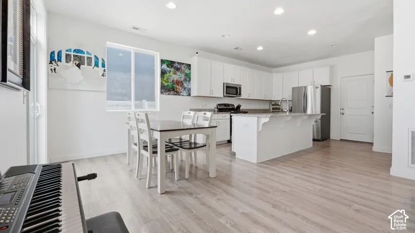 Open-concept layout connecting the kitchen and dining space, with a peninsula island and a rear entry door.