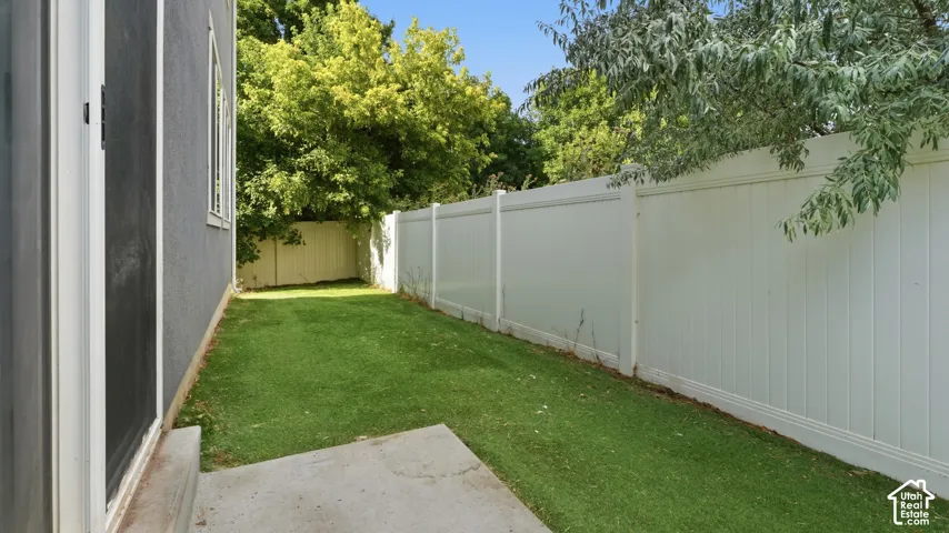 Back yard with artificial turf and white vinyl privacy fencing, offering additional outdoor space.