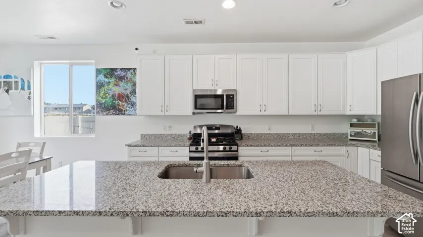 Detailed view of the granite island countertop with undermount sink and gas range, framed by white cabinetry.