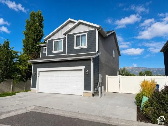 Two-tone exterior with gray siding and stucco accents, two-car garage, extra parking space on side, and a private side gate leading to the backyard.