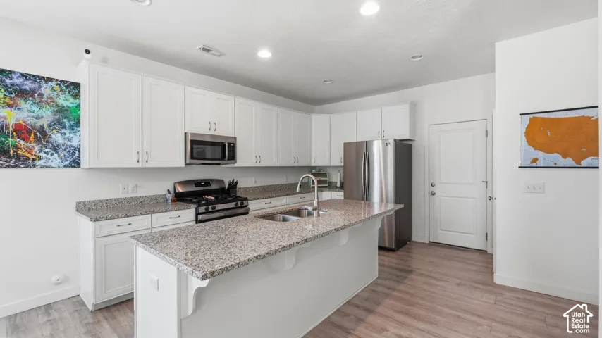 Spacious kitchen island with granite countertop and stainless sink, gas range, and stainless refrigerator, plus a rear door for backyard access.