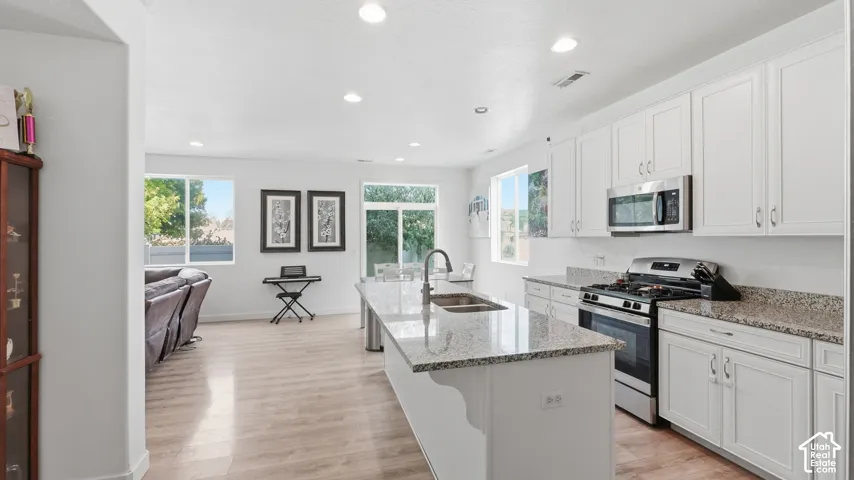 Kitchen with granite counters and stainless appliances opening into the adjoining living area, with natural light from multiple windows.