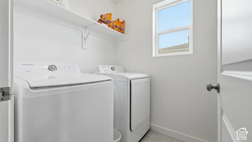 Dedicated laundry room with tile flooring, a window for natural light, and a shelf for storage.