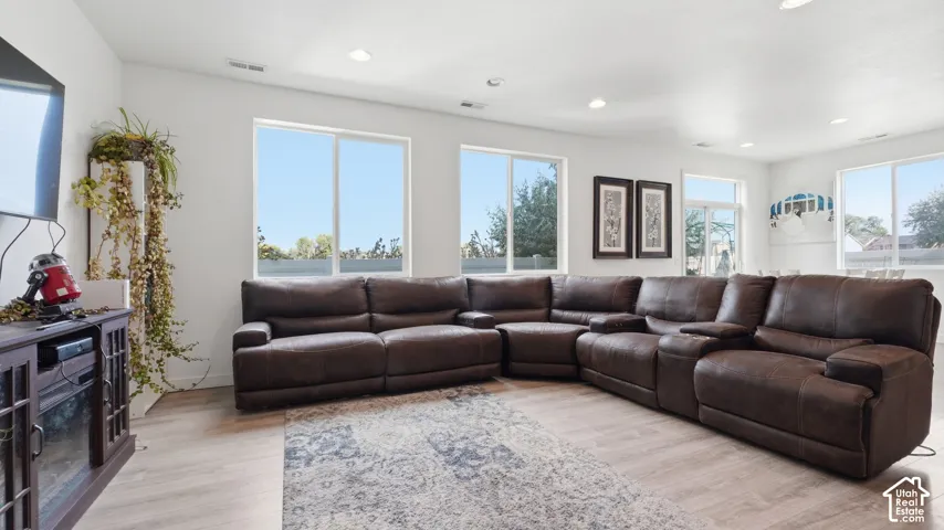 Spacious living area featuring recessed lighting, oversized windows for natural light, and durable wood-look flooring.