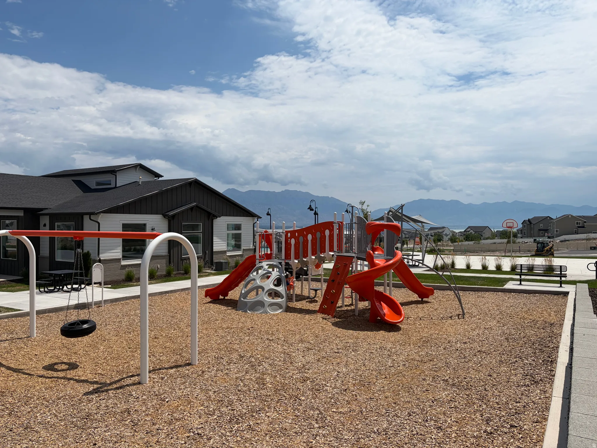 Community playground with multiple slides, swing set, and a basketball hoop
