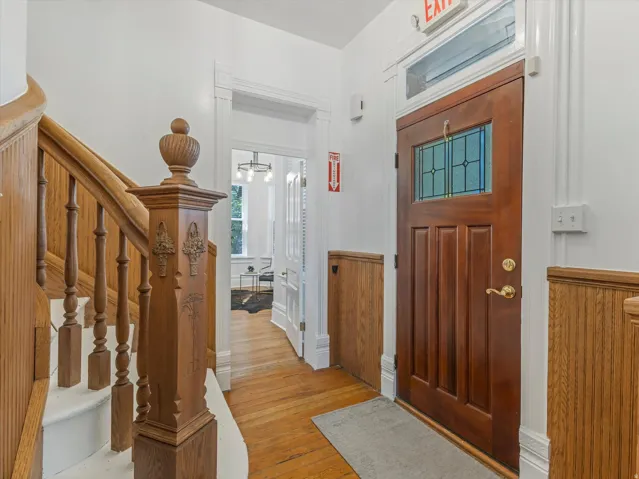 Hardwood flooring throughout the entryway, featuring an ornate wood staircase with a decorative newel post
