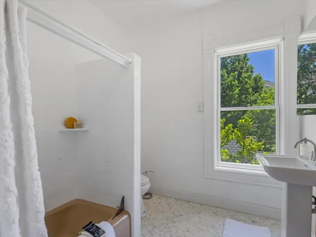 Bathroom featuring a pedestal sink, white tile flooring, and a window with natural light