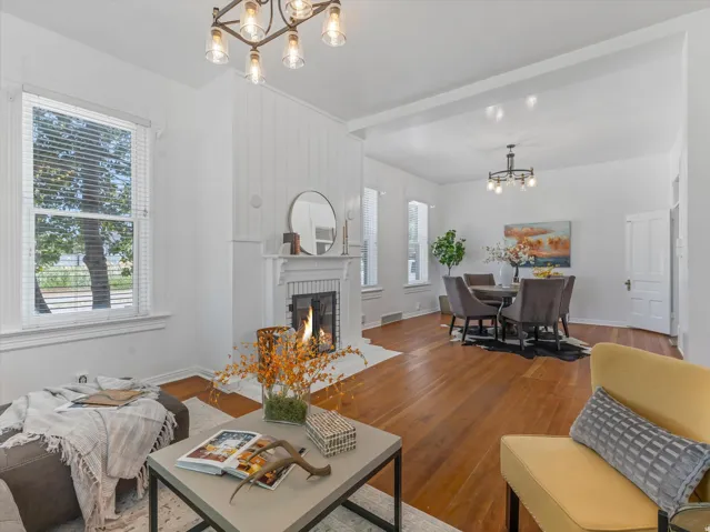 Spacious living area featuring a fireplace with a decorative mantel, wood-finish flooring, and bright windows