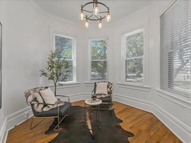 Corner room featuring multiple windows with blinds, wood-finish flooring, and a decorative ceiling light fixture