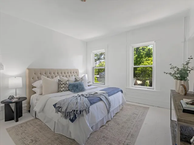 Bright room featuring two large windows with white trim, white walls, and light-toned wood-finish flooring