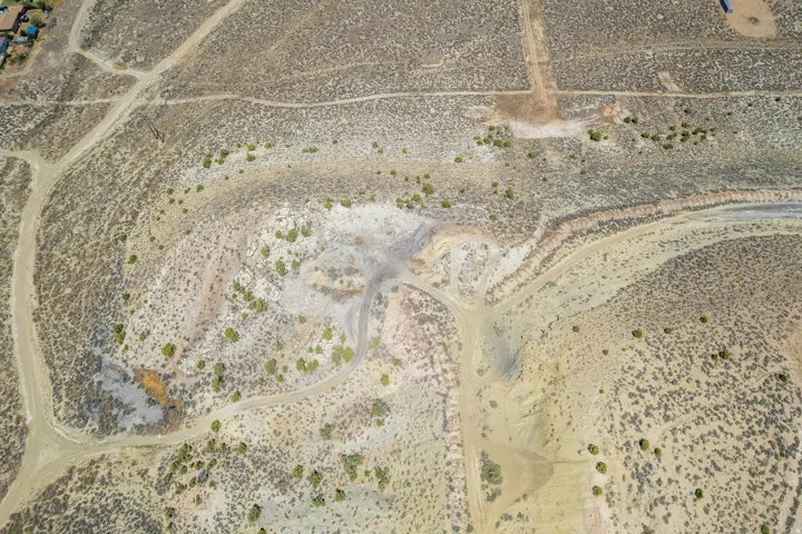 Expansive undeveloped terrain featuring varied topography, natural groundcover, multiple unpaved paths, distinct color variations in the earth, and scattered low-lying vegetation