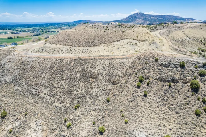 Expansive undeveloped land featuring natural desert vegetation, rolling terrain, distant mountain ranges, and clear blue skies