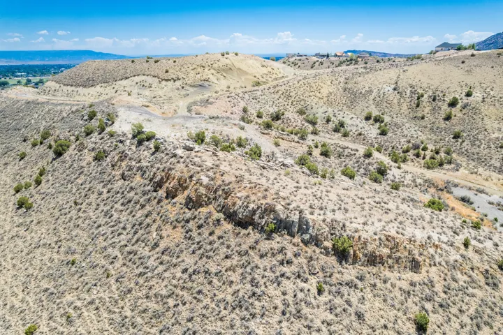 Expansive hillside property featuring diverse terrain, natural scrub brush, scattered juniper trees, and visible rock formations
