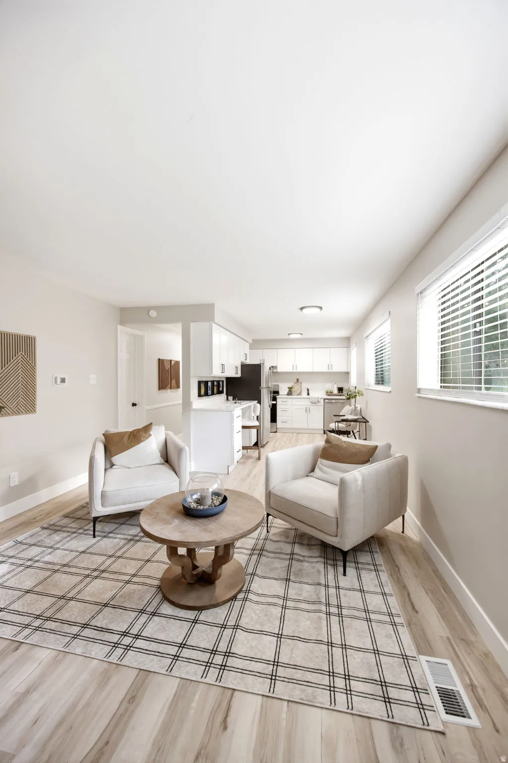 Spacious open-concept living area featuring light wood-finish flooring, recessed lighting, and ample natural light from multiple windows