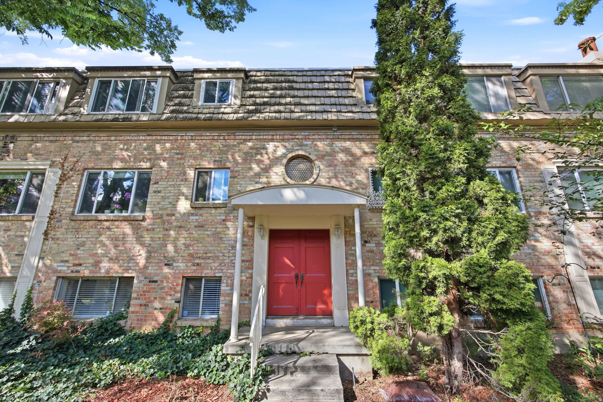 Brick facade building featuring a prominent red entry door with white portico