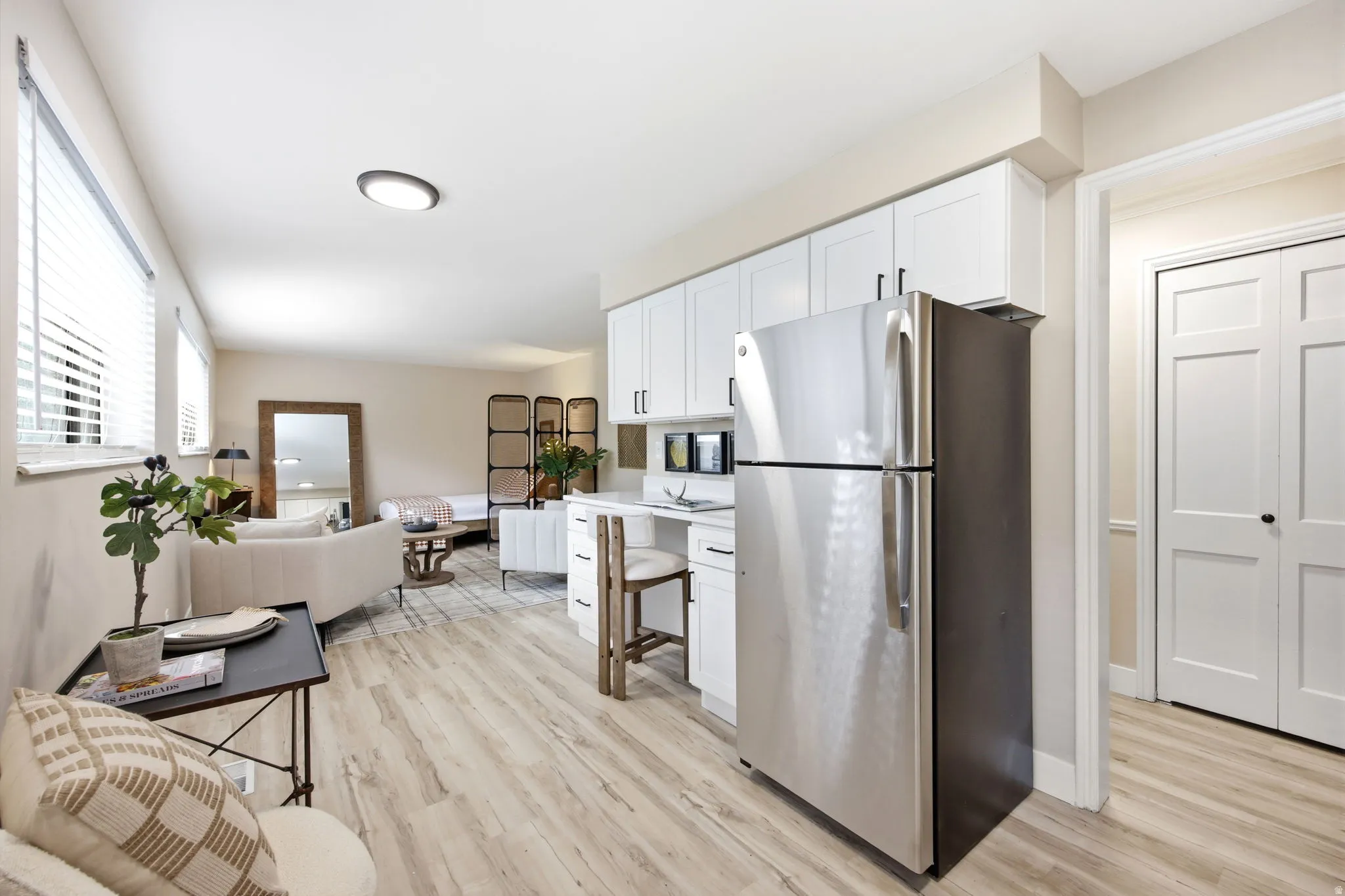 Open-concept living space featuring light wood-finish flooring, white walls, and recessed lighting