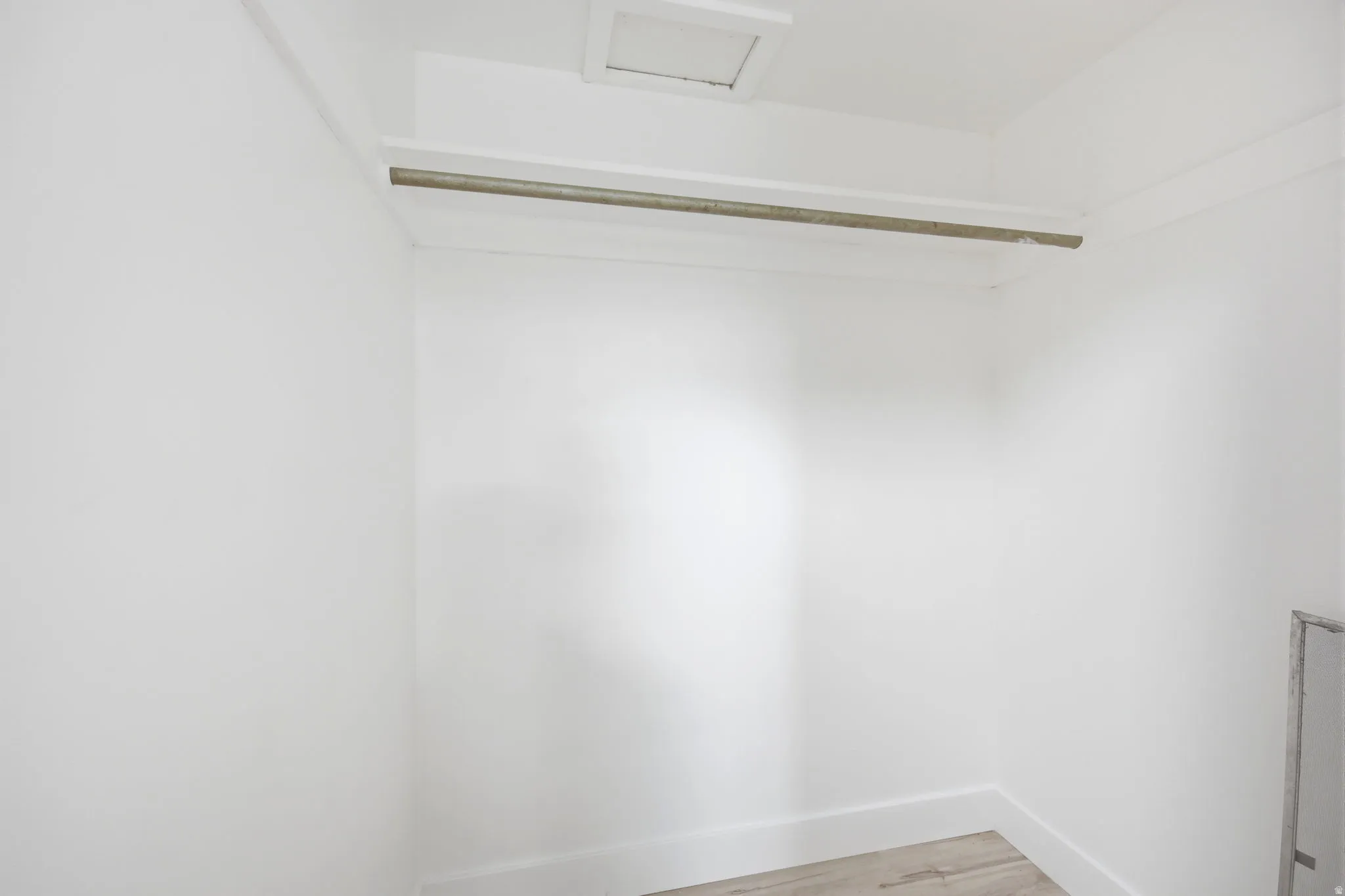 White walls and trim define this compact closet space, featuring a single hanging rod