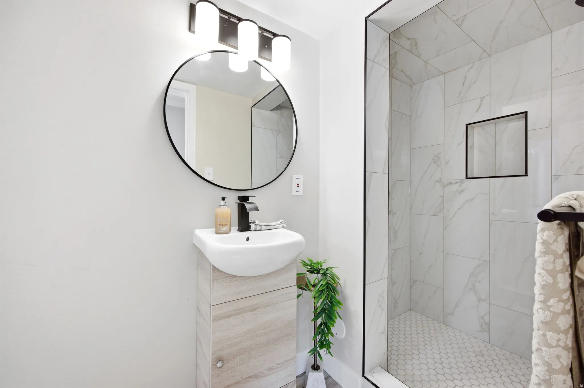 Modern bathroom featuring a contemporary vanity with an integrated sink, a circular black-framed mirror, and a sleek black faucet