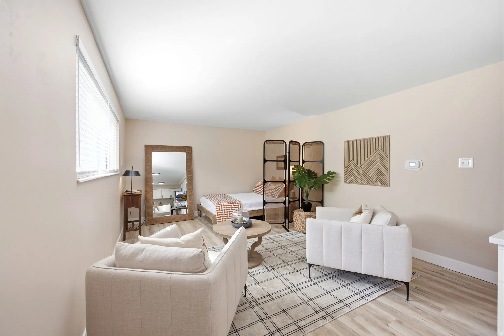 Open-concept living space with light wood-finish flooring, a contemporary room divider, and a window with horizontal blinds