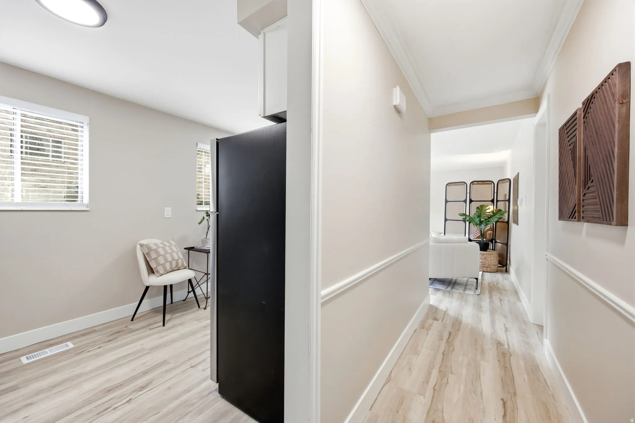 Hallway featuring wood-finish flooring, crown molding, and wainscoting