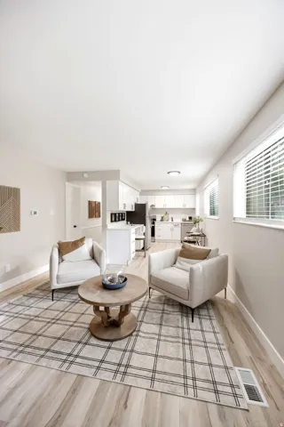 Spacious open-concept living area featuring light wood-finish flooring, recessed lighting, and ample natural light from multiple windows