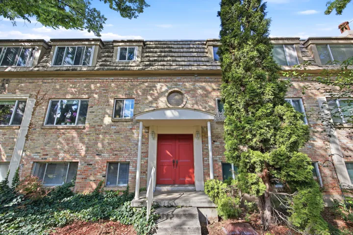 Brick facade building featuring a prominent red entry door with white portico