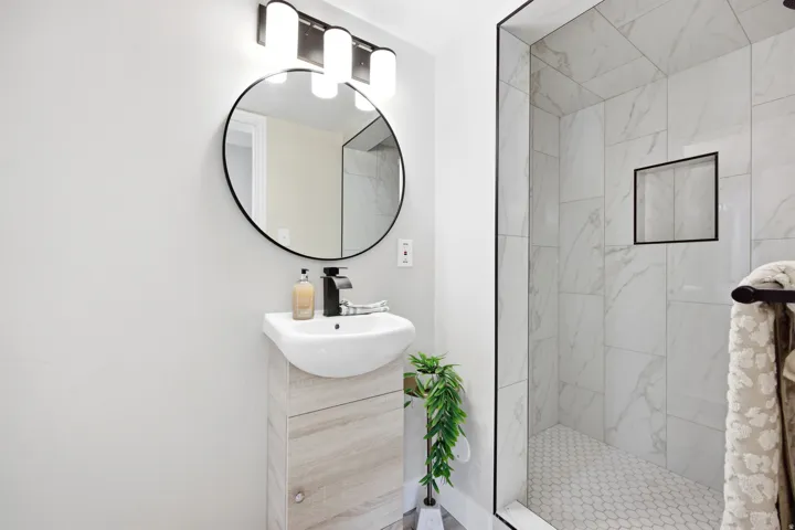 Modern bathroom featuring a contemporary vanity with an integrated sink, a circular black-framed mirror, and a sleek black faucet