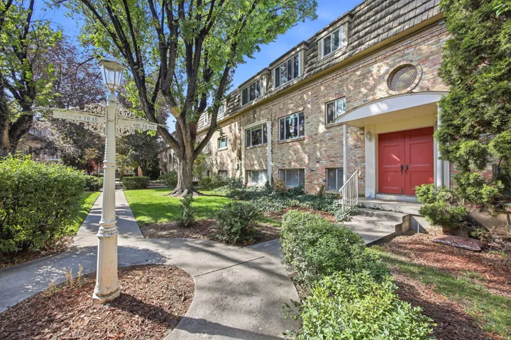 Brick facade building featuring a prominent red double-door entry with arched portico, a round architectural window, and a shingled mansard roof