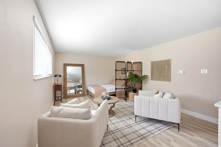 Open-concept living space with light wood-finish flooring, a contemporary room divider, and a window with horizontal blinds