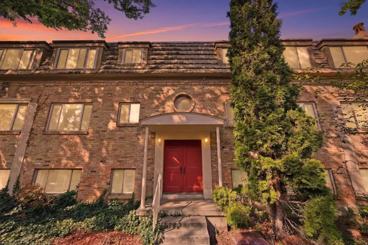 Brick exterior featuring a bright red double entry door with an arched portico