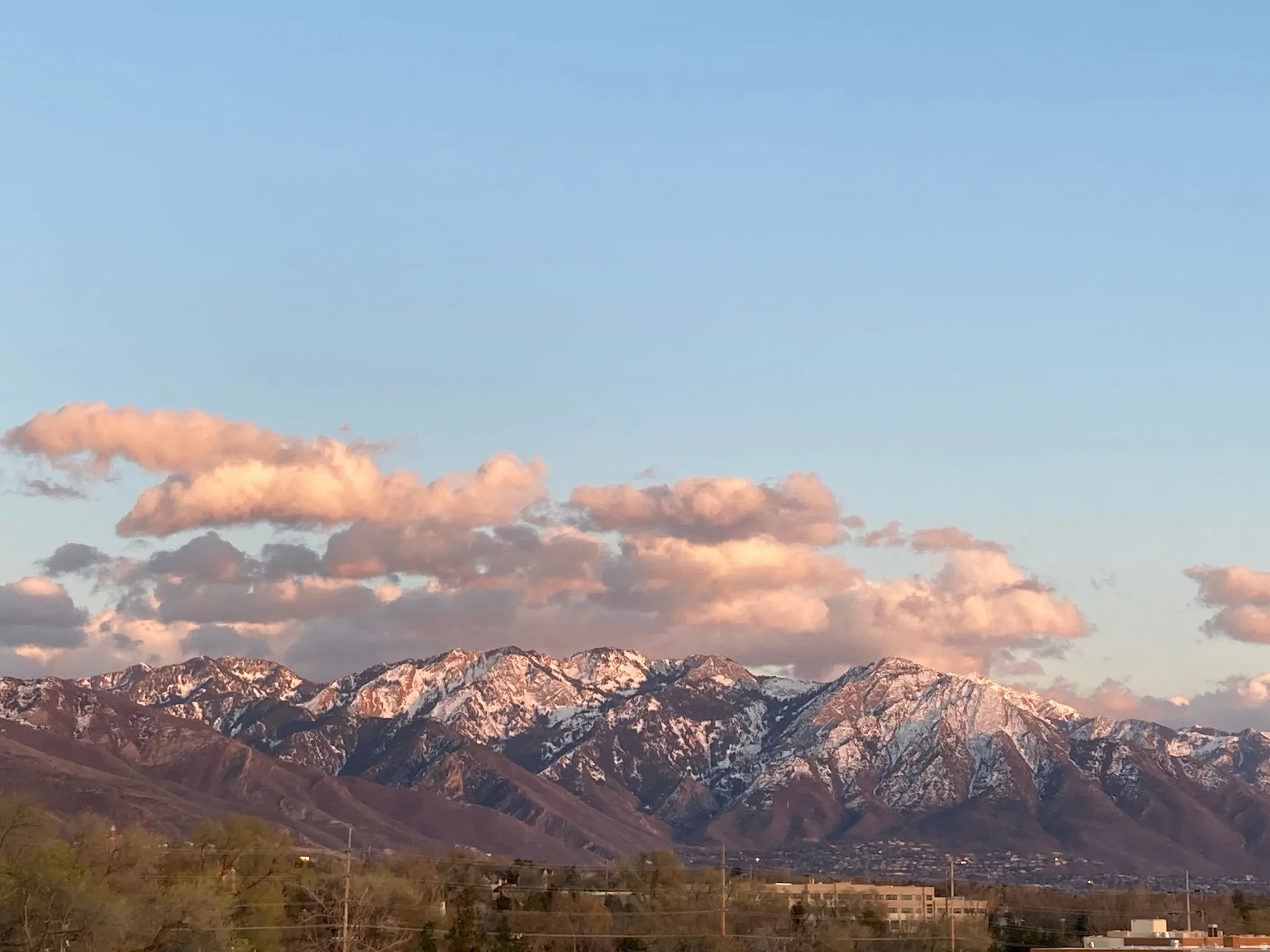 Mountain range featuring snow-capped peaks under a light blue sky with scattered clouds