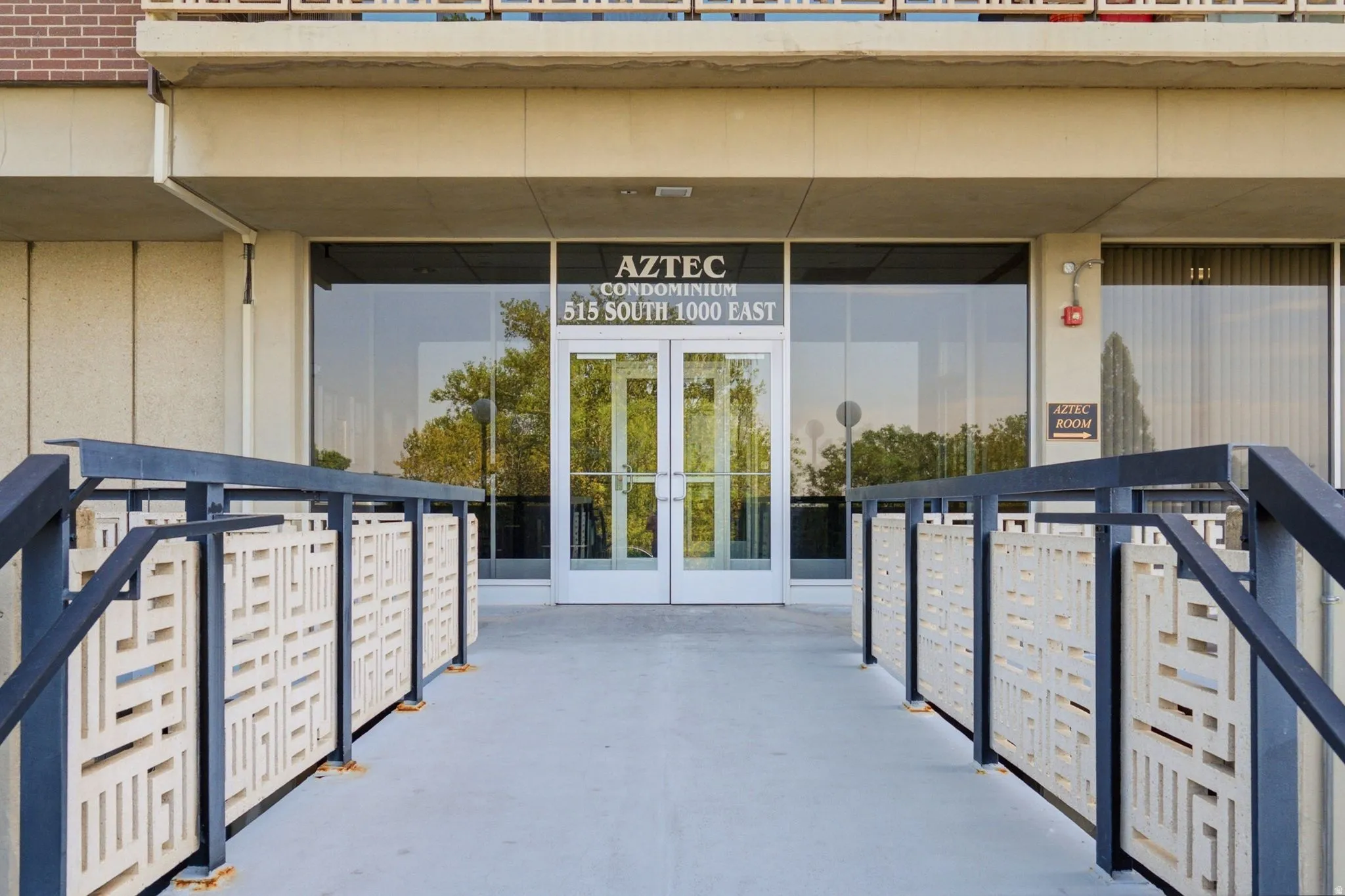 Building entrance featuring glass double doors, metal railings, and decorative patterned panels