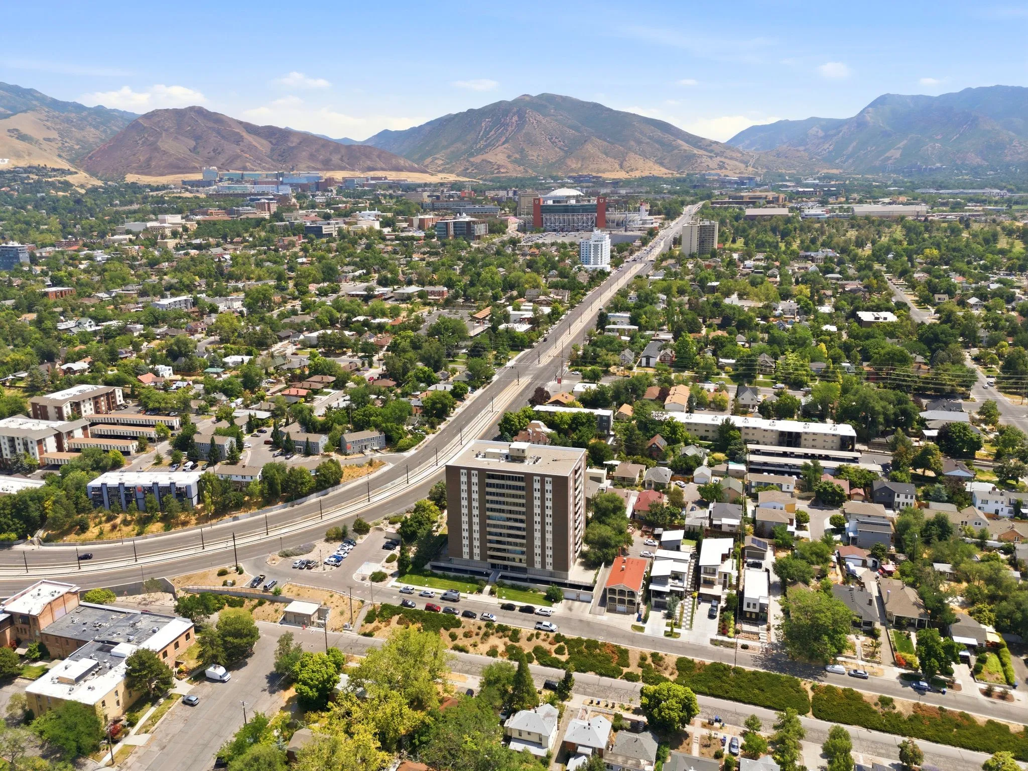 Elevated urban setting with a prominent high-rise building, surrounded by a residential area with mature trees and a substantial roadway
