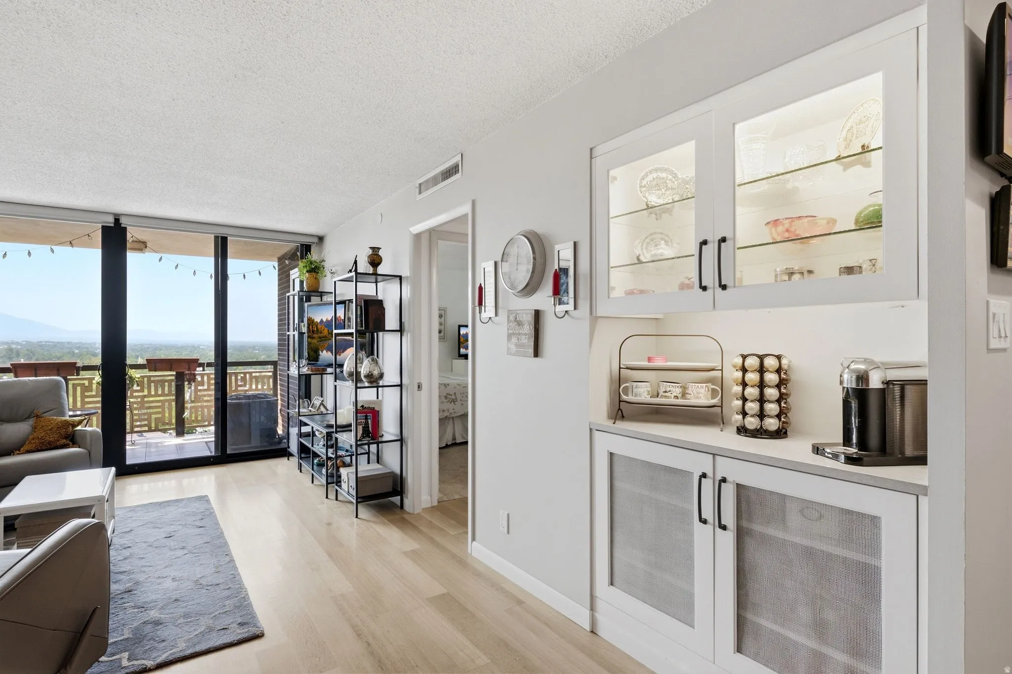 Living area with light wood-finish flooring extending to a full-height glass sliding door
