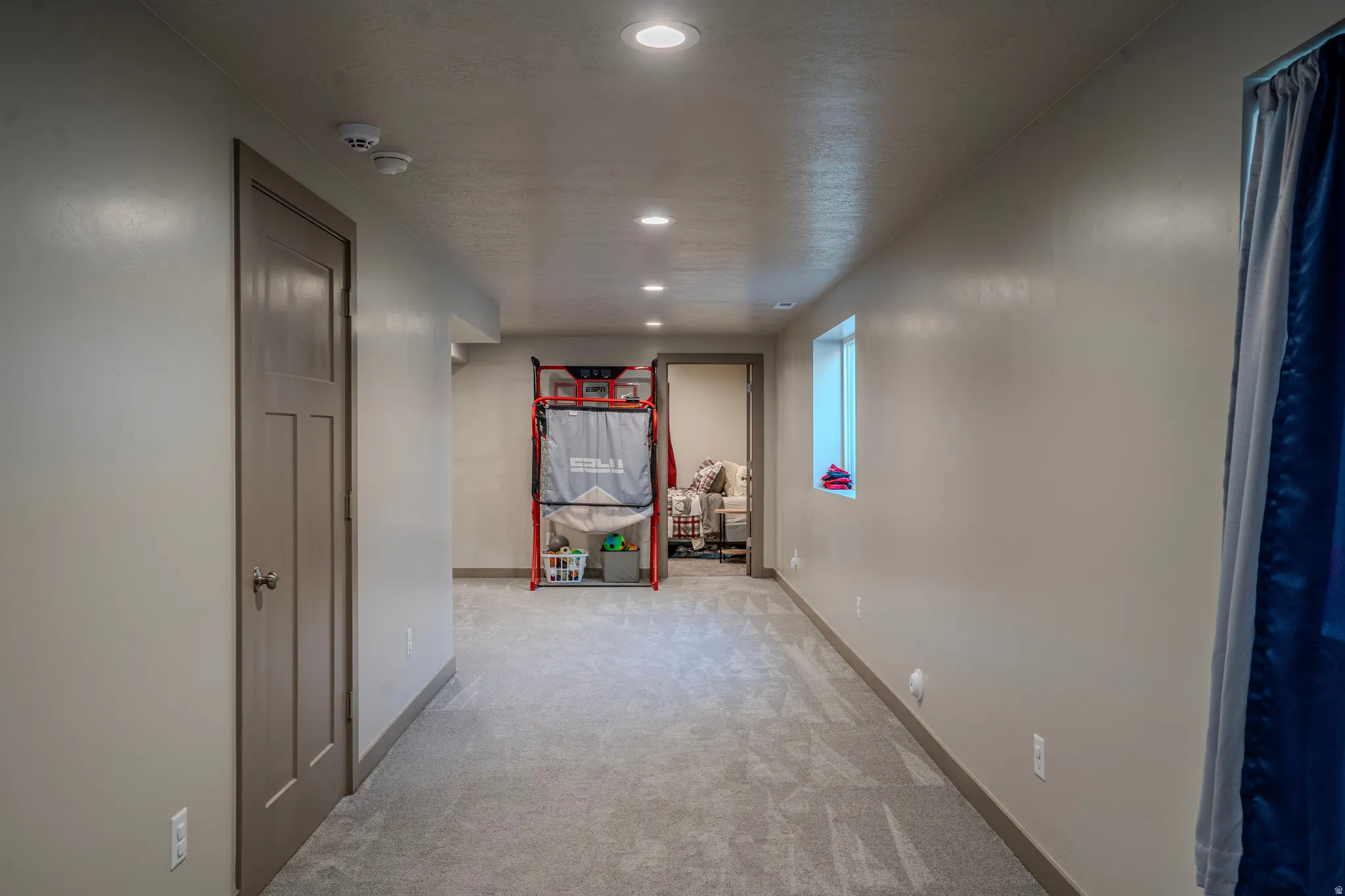 Hallway featuring recessed lighting, a neutral gray carpet, a single window, and a paneled door