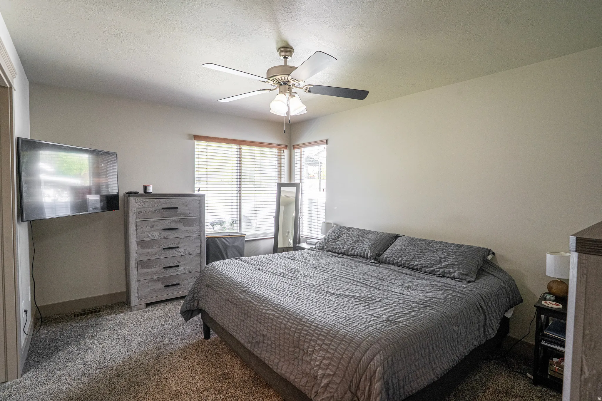 Carpeted room featuring a ceiling fan with integrated lighting, wood-finish window blinds, and light-toned wall paint